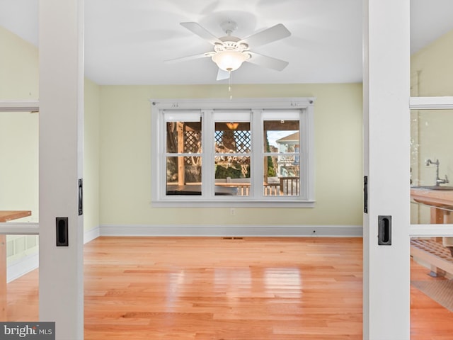 unfurnished room featuring hardwood / wood-style floors, ceiling fan, and sink