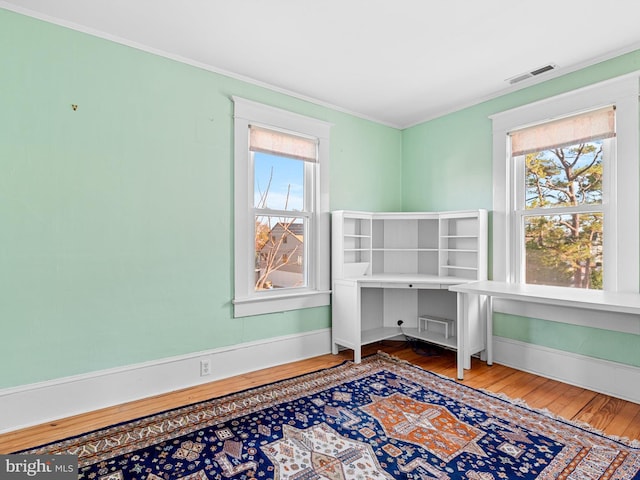 office featuring hardwood / wood-style flooring, crown molding, and a healthy amount of sunlight