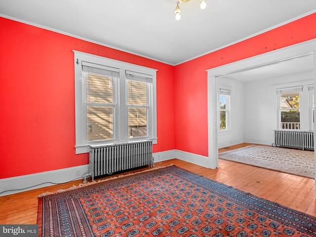 spare room with crown molding, radiator heating unit, and hardwood / wood-style floors