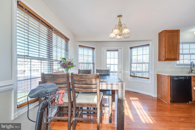 dining space with light hardwood / wood-style flooring, an inviting chandelier, and sink