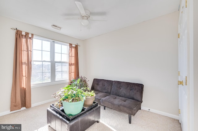 living area featuring light colored carpet and ceiling fan