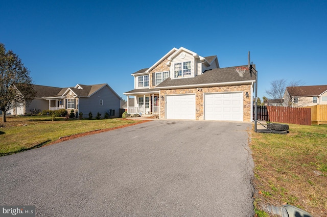 view of front of home with covered porch, a garage, and a front lawn