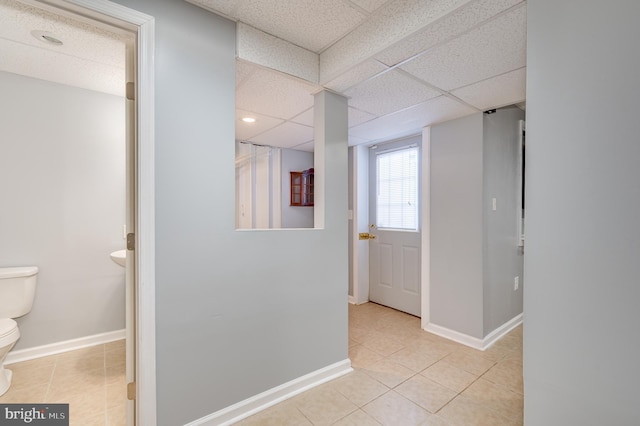 hallway featuring a drop ceiling and light tile patterned flooring