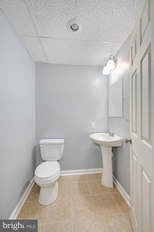 bathroom featuring tile patterned flooring, a paneled ceiling, and toilet