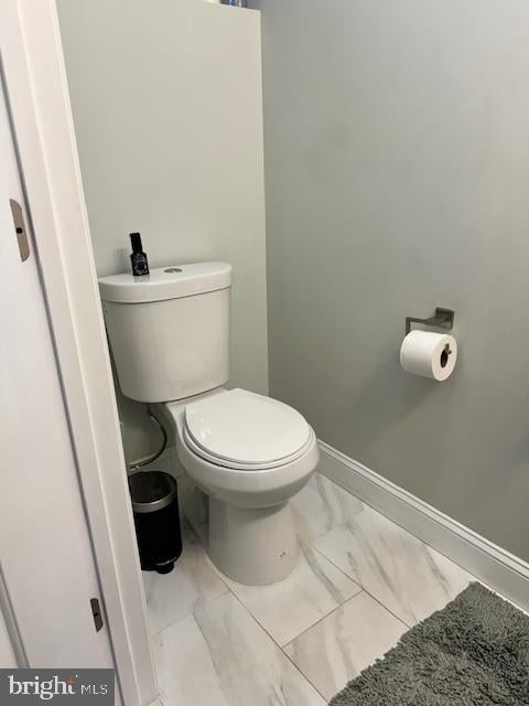 bathroom with baseboards, toilet, and marble finish floor