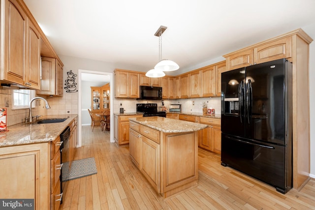 kitchen featuring light wood-type flooring, sink, black appliances, pendant lighting, and a kitchen island