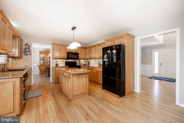 kitchen featuring decorative backsplash, sink, black appliances, light hardwood / wood-style flooring, and a center island