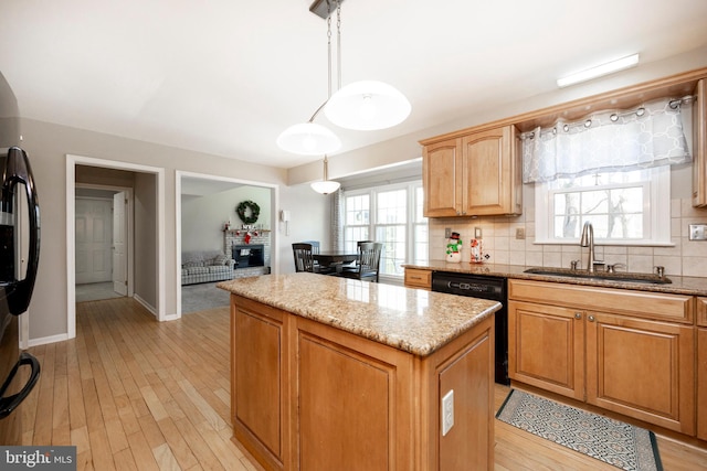 kitchen featuring pendant lighting, a center island, sink, black dishwasher, and light hardwood / wood-style floors