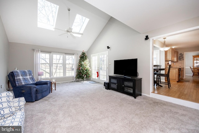 living room featuring light wood-type flooring, a skylight, ceiling fan, sink, and high vaulted ceiling