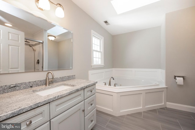 bathroom featuring vanity, shower with separate bathtub, and a skylight