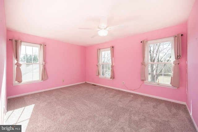 carpeted spare room featuring ceiling fan and plenty of natural light