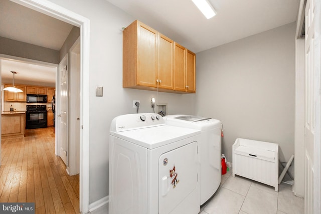 washroom featuring cabinets, washing machine and dryer, and light hardwood / wood-style flooring