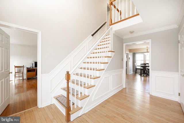 stairs featuring hardwood / wood-style floors and ornamental molding