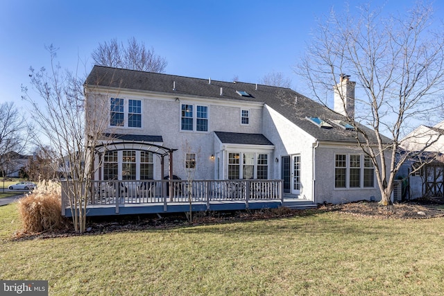 rear view of property featuring a lawn and a deck