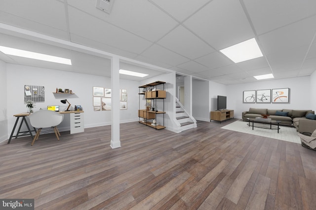 finished basement featuring visible vents, stairway, wood finished floors, and a paneled ceiling