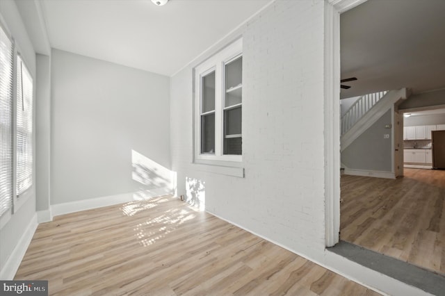 empty room with ceiling fan, a healthy amount of sunlight, and light hardwood / wood-style flooring