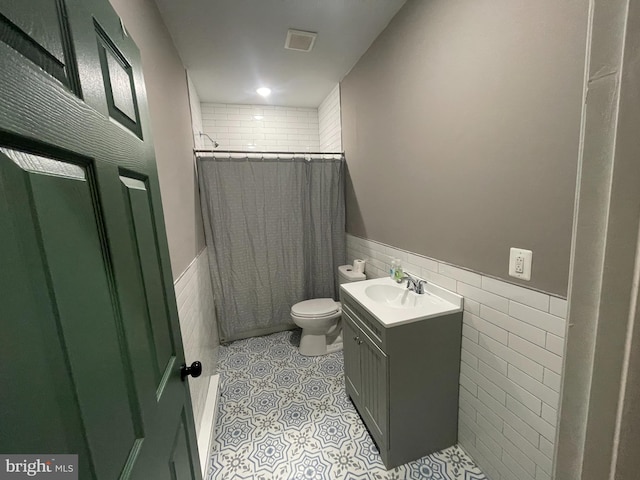 bathroom with tile patterned floors, a shower with curtain, vanity, tile walls, and toilet