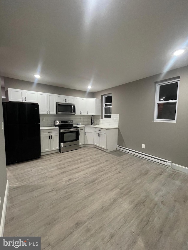 kitchen with light wood-type flooring, stainless steel appliances, sink, a baseboard radiator, and white cabinetry