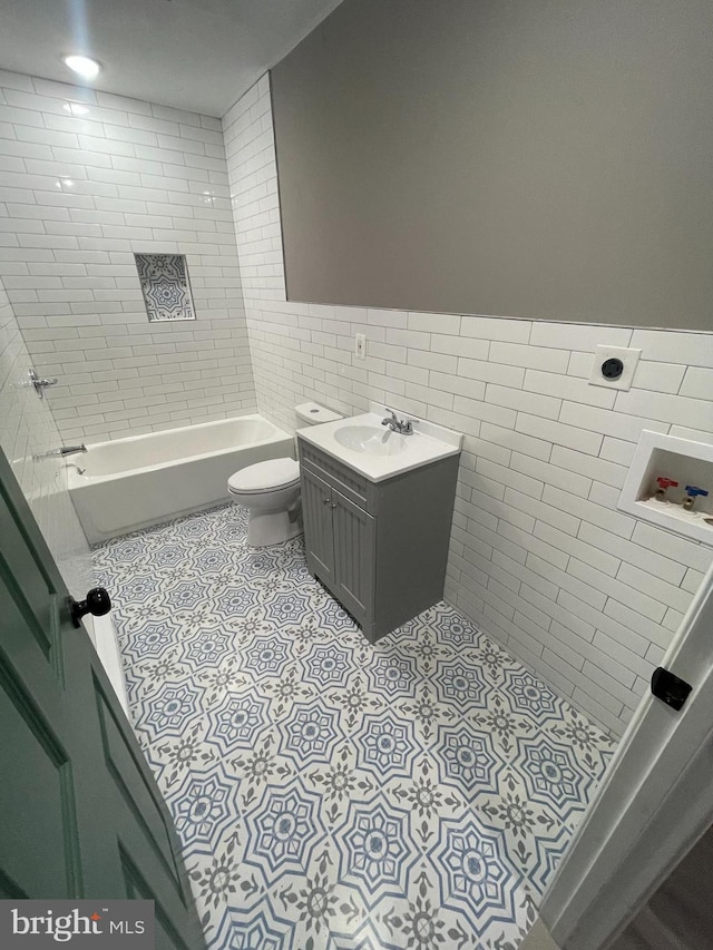 full bathroom with vanity, tile patterned flooring, tiled shower / bath combo, toilet, and tile walls