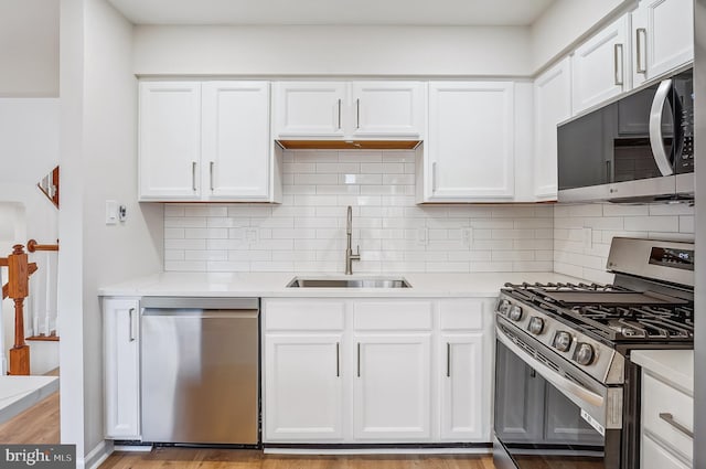 kitchen with backsplash, sink, appliances with stainless steel finishes, light hardwood / wood-style floors, and white cabinetry