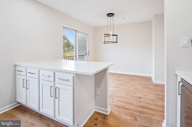 kitchen featuring light stone countertops, hanging light fixtures, kitchen peninsula, white cabinets, and light wood-type flooring