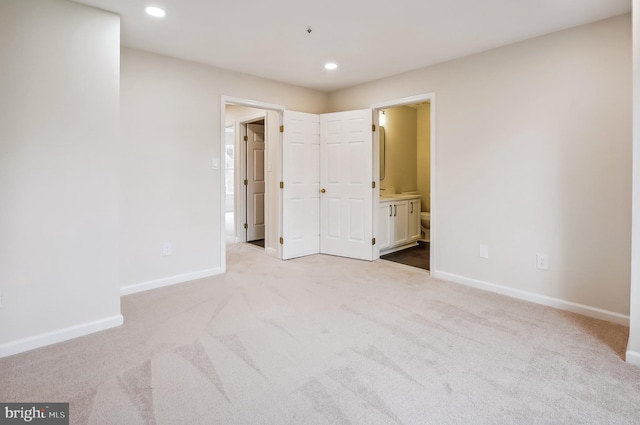 unfurnished bedroom featuring ensuite bath and light colored carpet