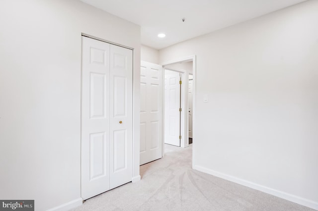 unfurnished bedroom featuring light carpet and a closet