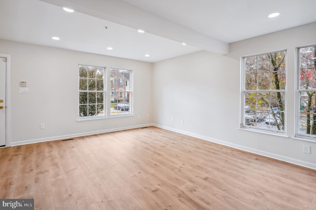 empty room featuring beamed ceiling and light hardwood / wood-style floors