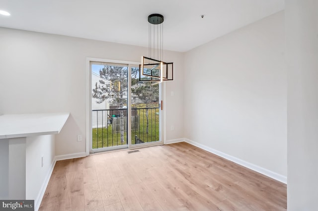 unfurnished dining area featuring light hardwood / wood-style flooring and an inviting chandelier