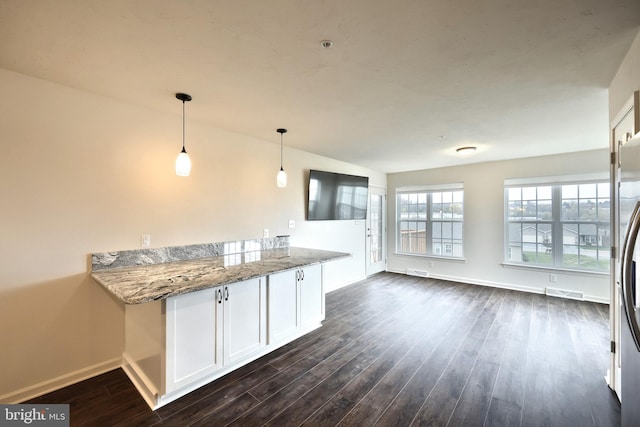 kitchen featuring pendant lighting, dark wood-type flooring, white cabinets, light stone countertops, and kitchen peninsula