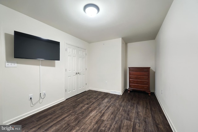 unfurnished bedroom featuring a closet and dark wood-type flooring