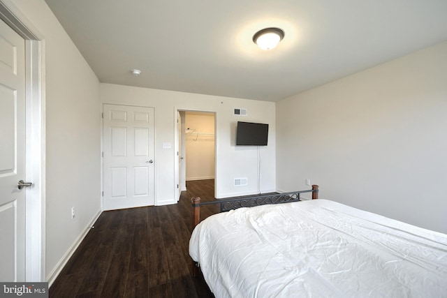 bedroom featuring a spacious closet, a closet, and dark wood-type flooring