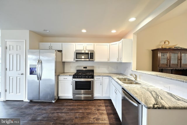 kitchen with appliances with stainless steel finishes, dark hardwood / wood-style flooring, light stone counters, sink, and white cabinetry