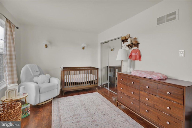 bedroom with dark hardwood / wood-style floors, a closet, and a nursery area