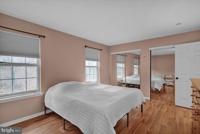 bedroom with light hardwood / wood-style floors and multiple windows