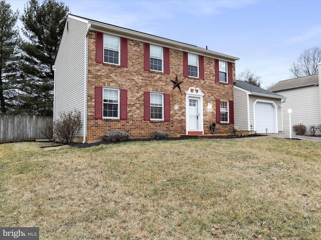 colonial home with a garage, brick siding, fence, and a front lawn