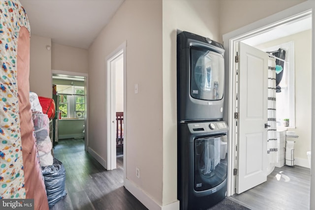 laundry room with dark wood-type flooring and stacked washing maching and dryer