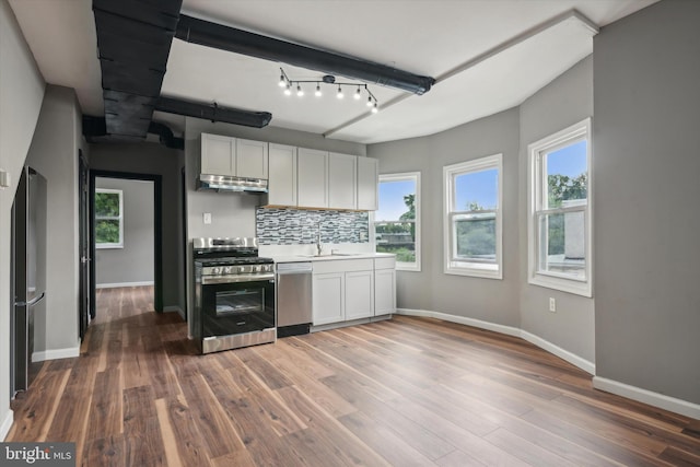 kitchen featuring backsplash, white cabinets, dark hardwood / wood-style floors, appliances with stainless steel finishes, and a healthy amount of sunlight