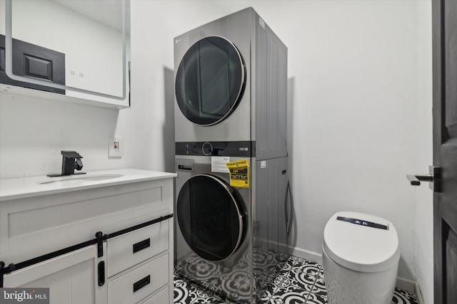 laundry room with tile patterned flooring, stacked washer / drying machine, and sink