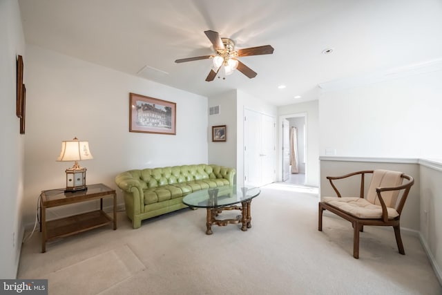 living room with ceiling fan, crown molding, and light carpet