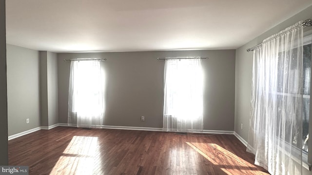 unfurnished room with a wealth of natural light and dark wood-type flooring