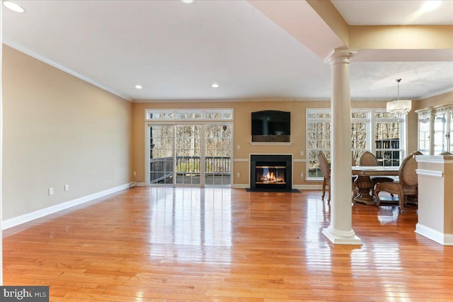 living room featuring a wealth of natural light, ornamental molding, and light wood-type flooring