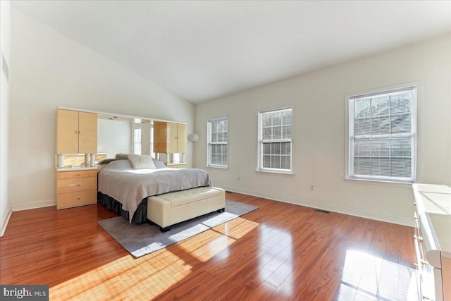 bedroom featuring hardwood / wood-style floors, multiple windows, and lofted ceiling