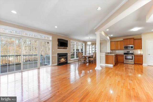 kitchen with light hardwood / wood-style floors, ornamental molding, sink, and appliances with stainless steel finishes