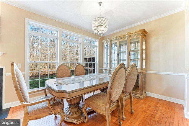 dining area featuring a chandelier, ornamental molding, and light hardwood / wood-style flooring