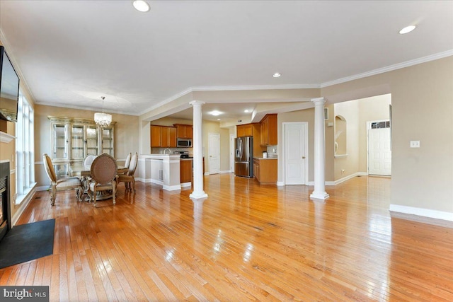 living room featuring a notable chandelier, ornamental molding, and light hardwood / wood-style flooring