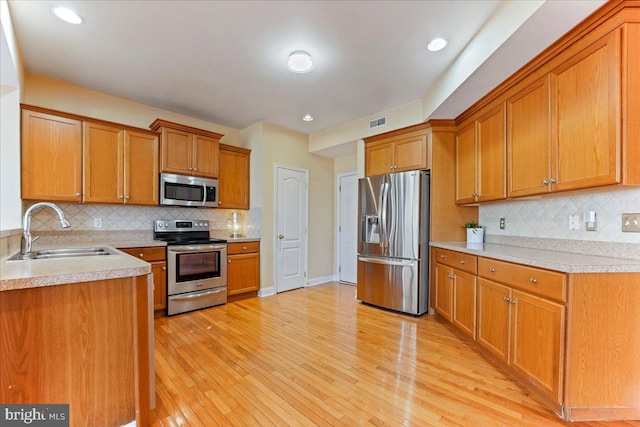 kitchen featuring light hardwood / wood-style floors, sink, stainless steel appliances, and tasteful backsplash