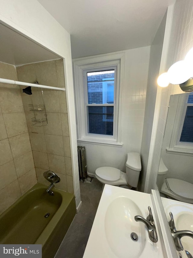 full bathroom featuring vanity, tiled shower / bath combo, and toilet