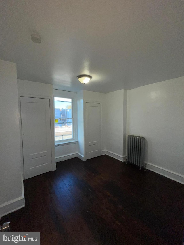 spare room featuring radiator heating unit and dark hardwood / wood-style floors