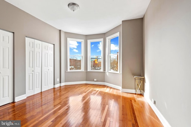 639 S Conkling St, Baltimore, MD 21224 - unfurnished bedroom with wood-type flooring, baseboards, and two closets